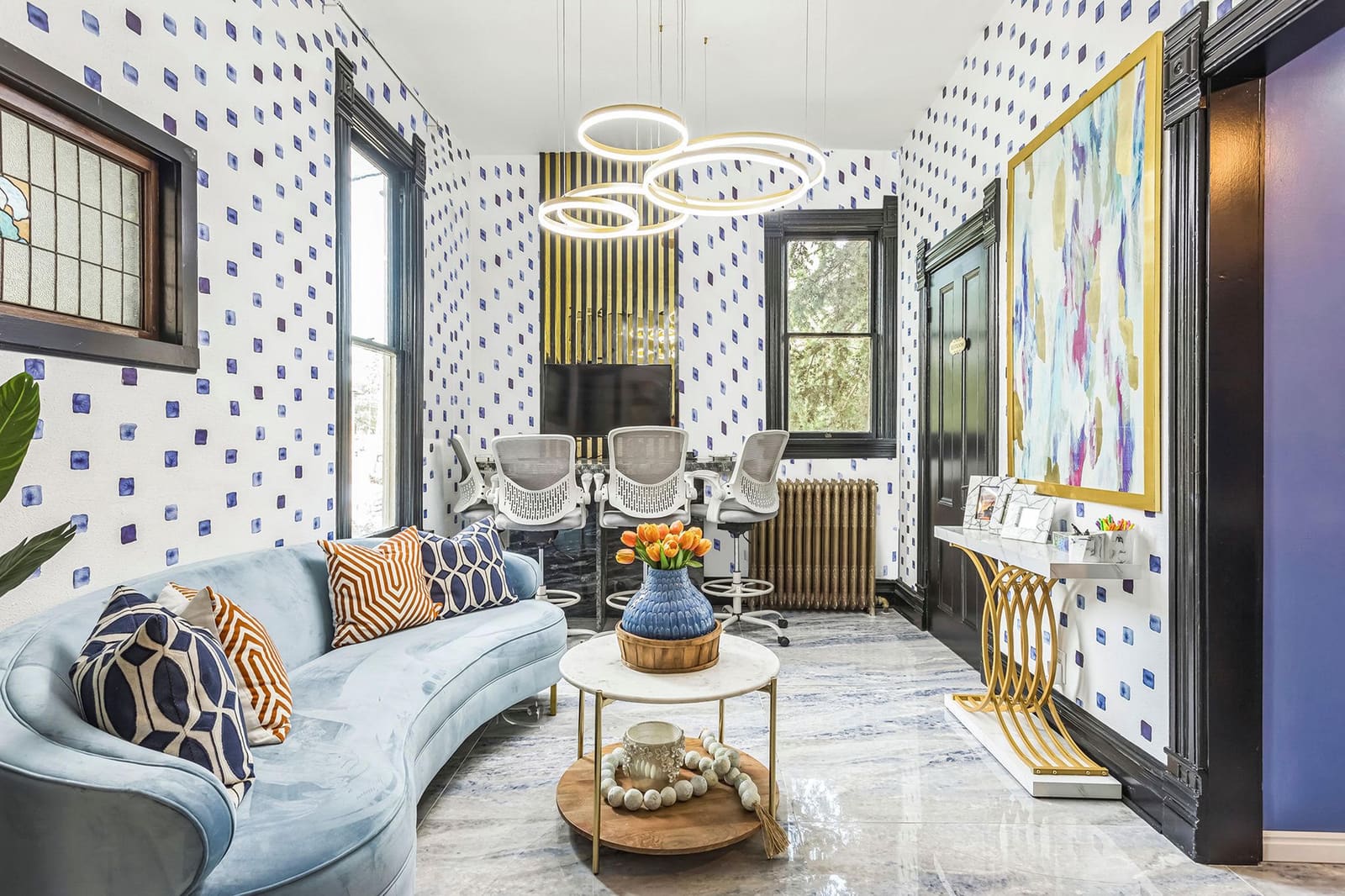 Lounge with blue dot wallpaper and gold ring chandeliers