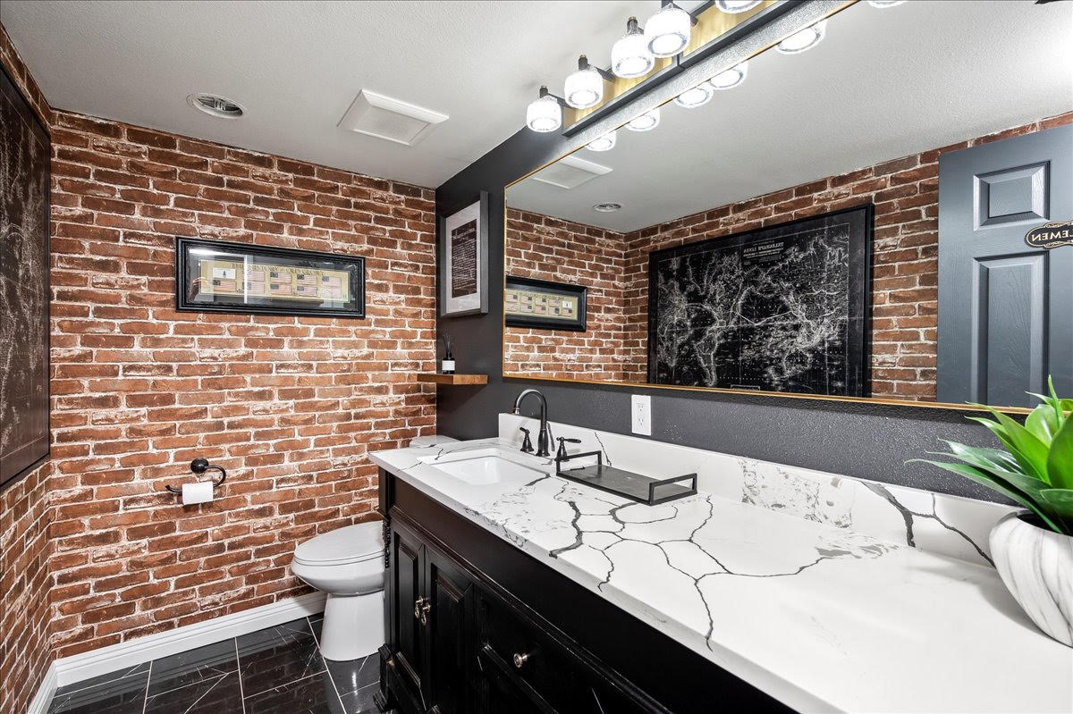 Restroom with exposed brick and marble vanity